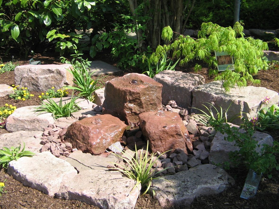 Steinbrunnen  mit grüner Bepflanzung